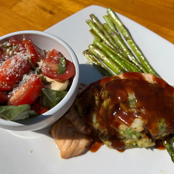 American dish with salmon, asparagus, and a side of tomato and mozzarella salad.