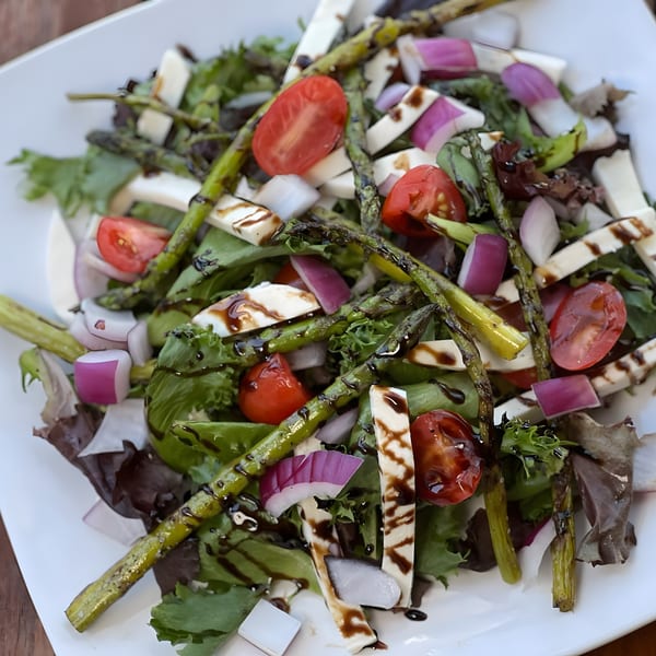 A vibrant Red Brick Station salad with grilled asparagus, tomatoes, red onion, and mozzarella on greens.