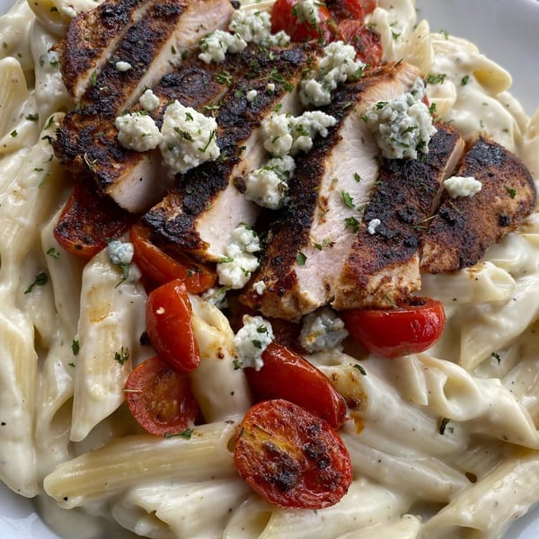 Blackened chicken and roasted tomatoes over creamy penne pasta, topped with crumbled blue cheese and herbs.