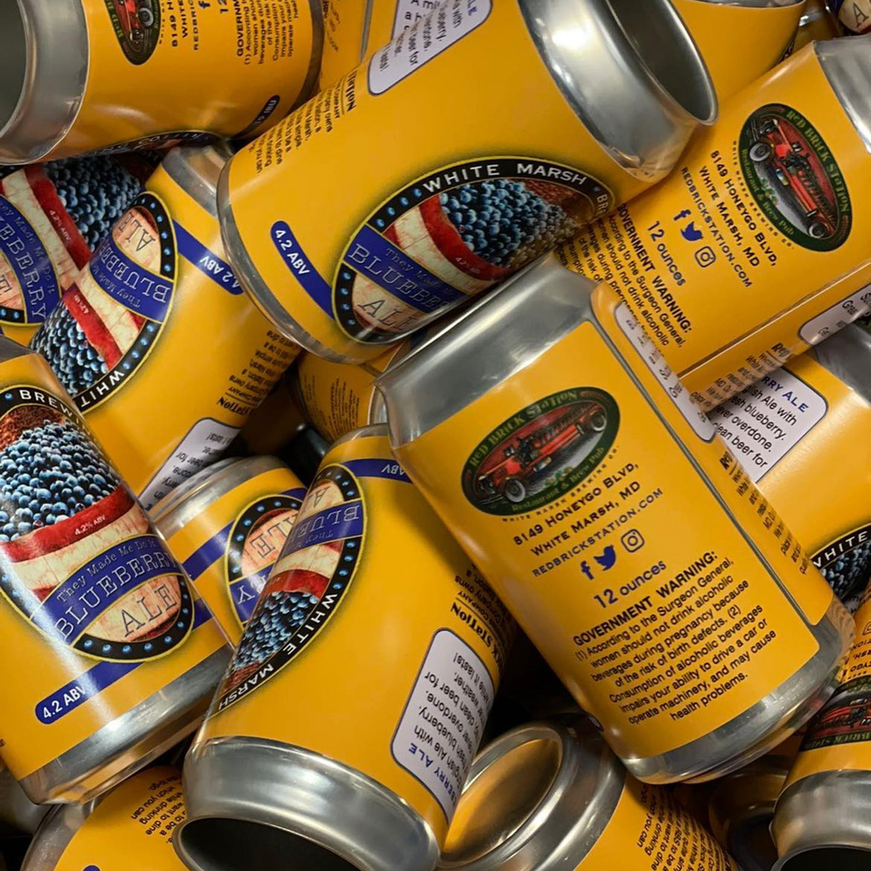 A close-up view of numerous Red Brick Station Blueberry Ale cans, featuring a patriotic label design.