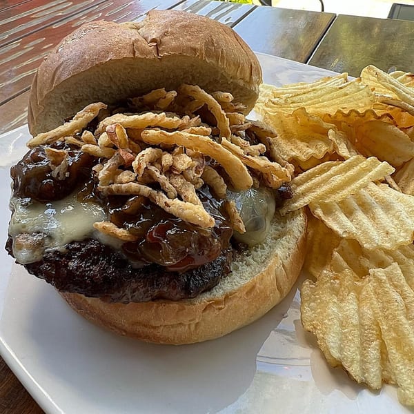 A Red Brick Station burger with caramelized onions, cheese, and crispy fried onions, served with waffle chips.