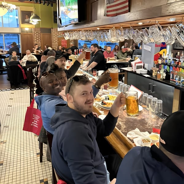 Patrons enjoying drinks and food at the Red Brick Station bar, with an American flag hanging above.