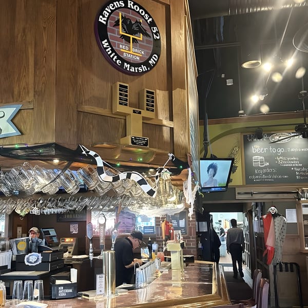 Interior of Red Brick Station bar with a bartender, patrons, and a Ravens Roost 52 sign.